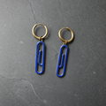 A pair of cobalt blue enamelled brass paperclip charm earrings on dark slate