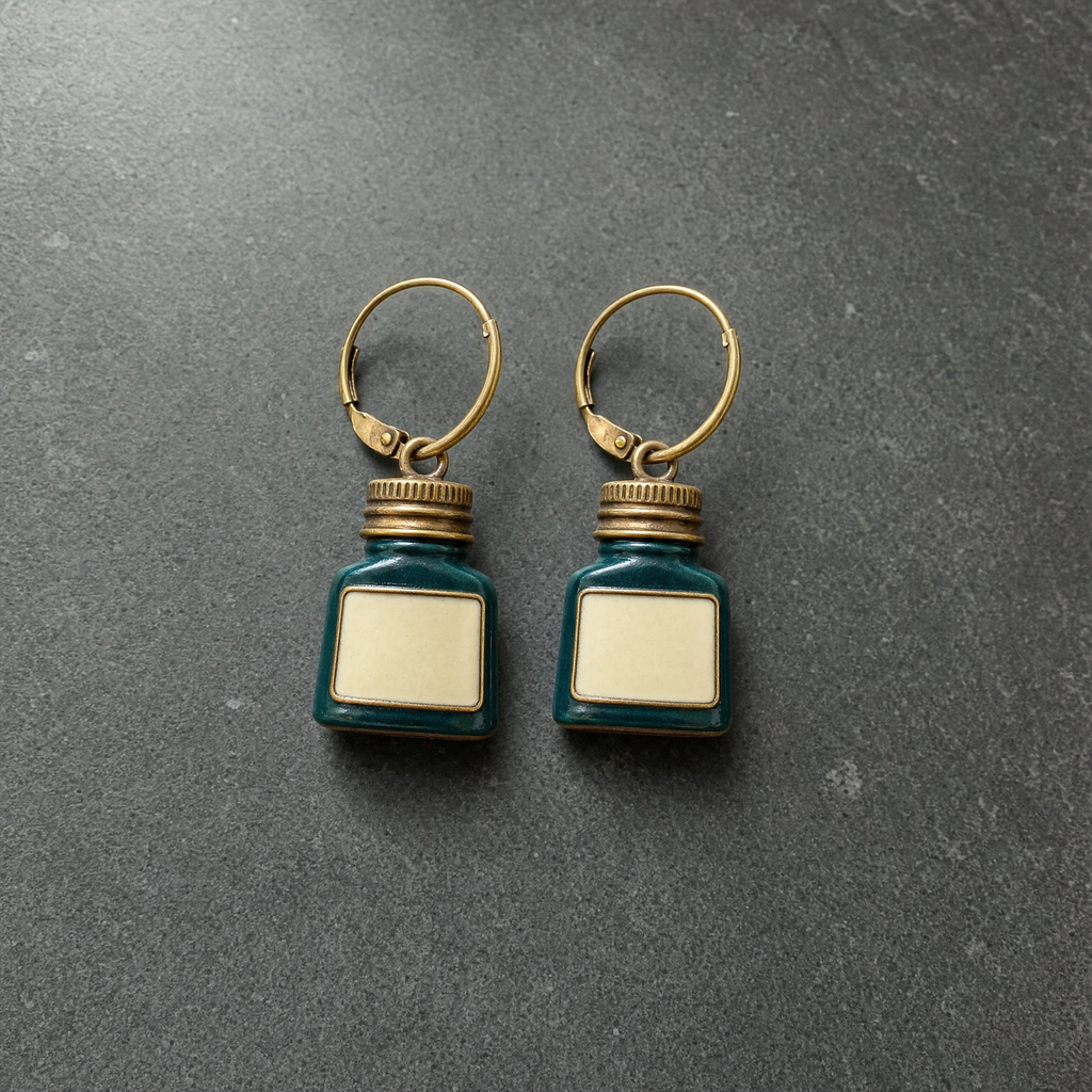 A pair of teal enamelled brass ink bottle charm earrings on dark slate