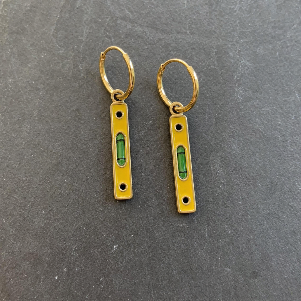 A pair of mustard enamelled brass spirit level charm earrings on dark slate