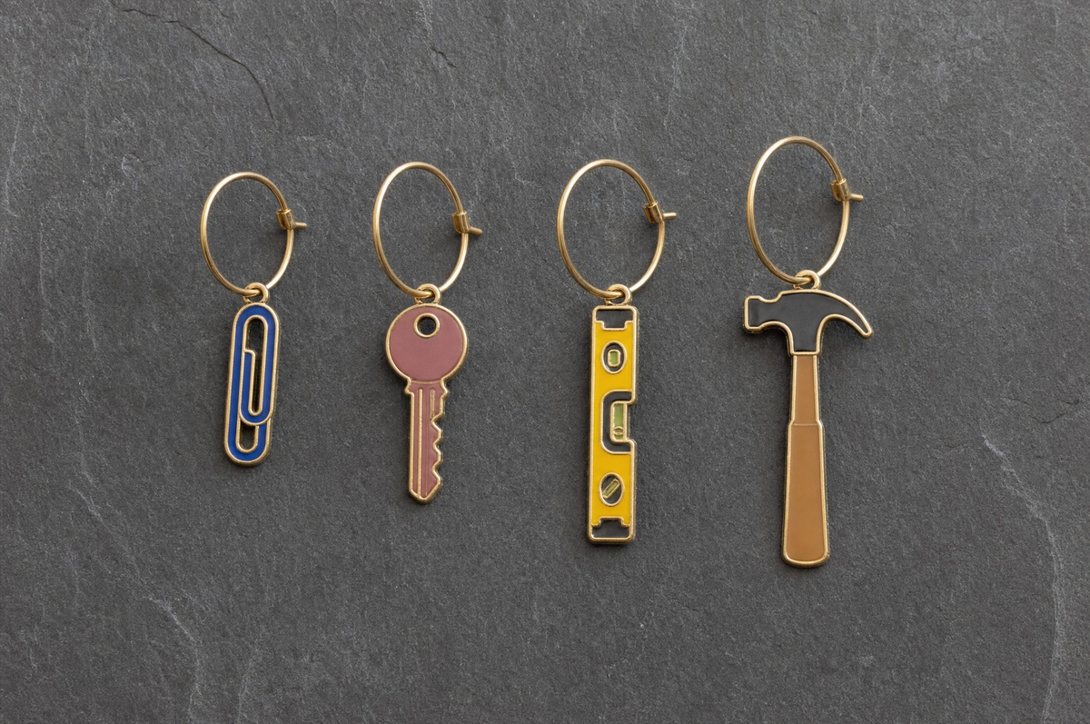 Paperclip, key, spirit level and claw hammer charms in a row at the same scale