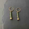 A pair of olive green enamelled brass pocket torch charm earrings on dark slate
